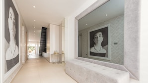 A modern hallway with a marble bench, a glass wall with a framed picture, and a staircase in the background. - Villa Magnolia Zadarvillas (Zadar)