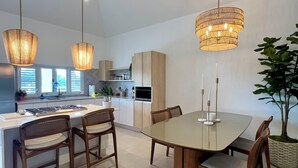 Una cocina moderna con una isla central, sillas de madera e iluminación colgante.