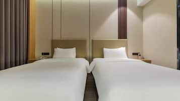 A hotel room with two beds, a wooden floor, and a modern design.
