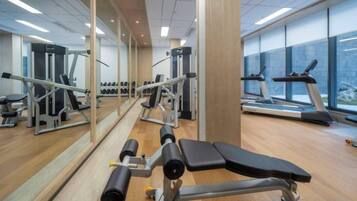 A gym with exercise equipment, mirrors, and treadmills.