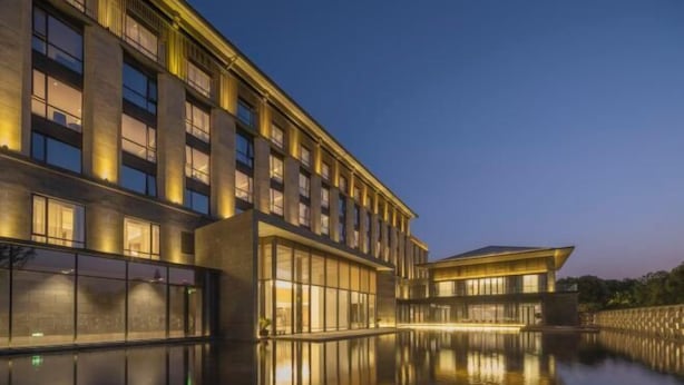 A modern hotel with a reflective pool, large windows, and a well-lit facade. - Wuhu Maison New Century Hotel (Wuhu)