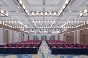 A large conference room with rows of tables and chairs, a high ceiling with modern lighting fixtures, and a carpeted floor. - Wuhu Maison New Century Hotel (Wuhu)
