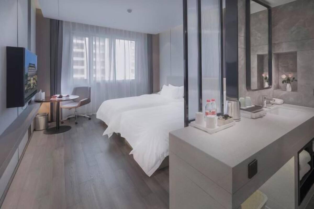 Een moderne hotelkamer met een groot bed, een bureau en een badkamer met een spiegel en wastafel.