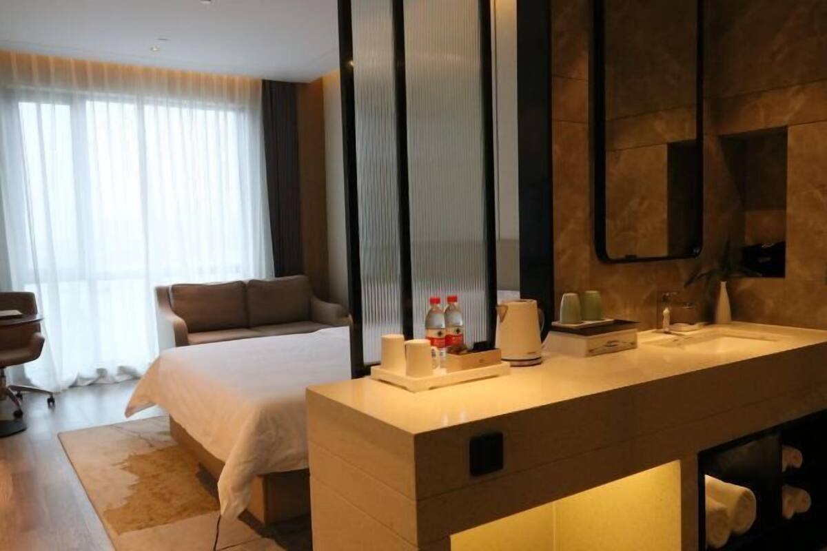 Hotelkamer met een groot bed, een moderne badkamer met een wastafel en een grote spiegel.