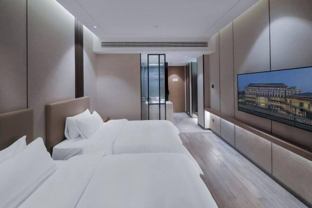 Een moderne hotelkamer met een groot bed, een televisie en uitzicht op een gebouw.