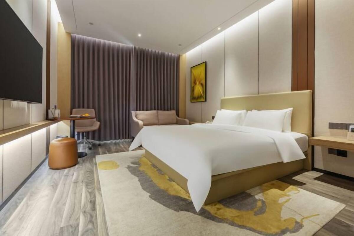 Een moderne hotelkamer met een groot bed, een flatscreen televisie, een bureau en een zithoek.