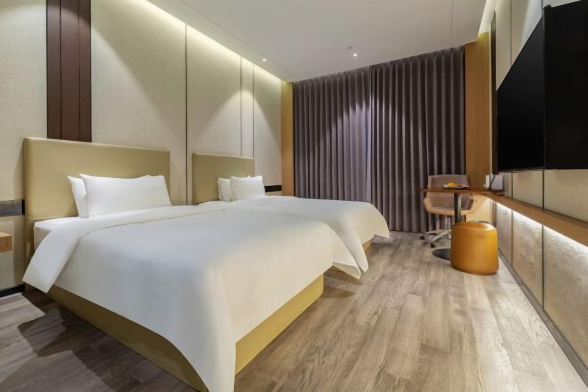 Una habitación de hotel moderna con una cama grande, un escritorio y una televisión.
