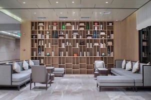 Un vestíbulo moderno con zona de estar, pared de estanterías y un mostrador de recepción.