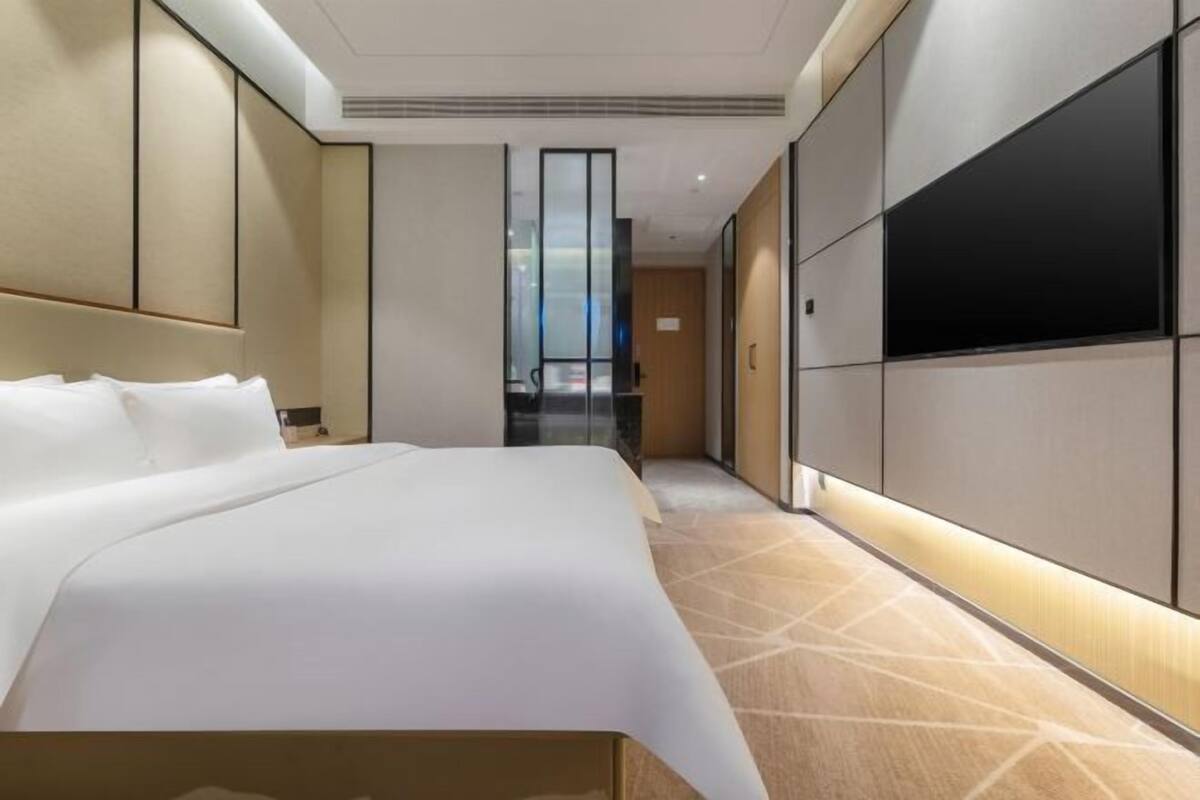 Een moderne hotelkamer met een groot bed, een flatscreen-tv en uitzicht op de stad.