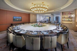 Une salle de conférence avec une table ronde, des chaises et un lustre.