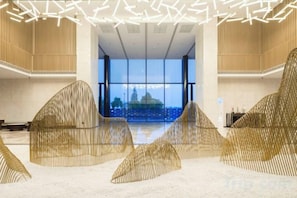 A spacious lobby with modern design, large windows, and unique sculptural seating. - Wuhu Maison New Century Hotel (Wuhu)