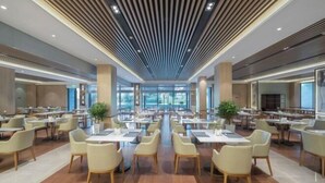 A spacious dining area with multiple tables and chairs, large windows, and a modern ceiling design. - Wuhu Maison New Century Hotel (Wuhu)