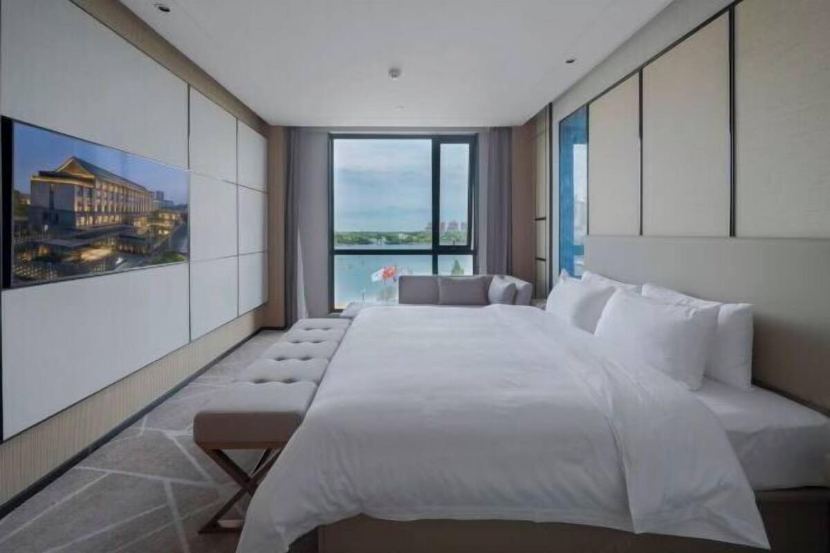 Een moderne hotelkamer met een groot bed, uitzicht op de stad en een balkon.