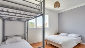 A dormitory room with bunk beds, a single bed, a window with a view, and a hanging light fixture. - 350m from the beach- House for 8- Large terrace (Saint-Hilaire-de-Riez)