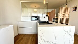 A modern kitchen with a marble countertop, a built-in microwave, and a sink. - Appartement Top Cocooning – Vue mer 180° (Quiberon)