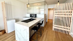 A compact kitchen with a marble countertop, a built-in microwave, and a black sink. - Appartement Top Cocooning – Vue mer 180° (Quiberon)