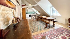 A loft-style room with a wooden bench, a patterned rug, and a stone wall. - Appartement de charme Cosy À 2 pas des plages (Larmor-Plage)