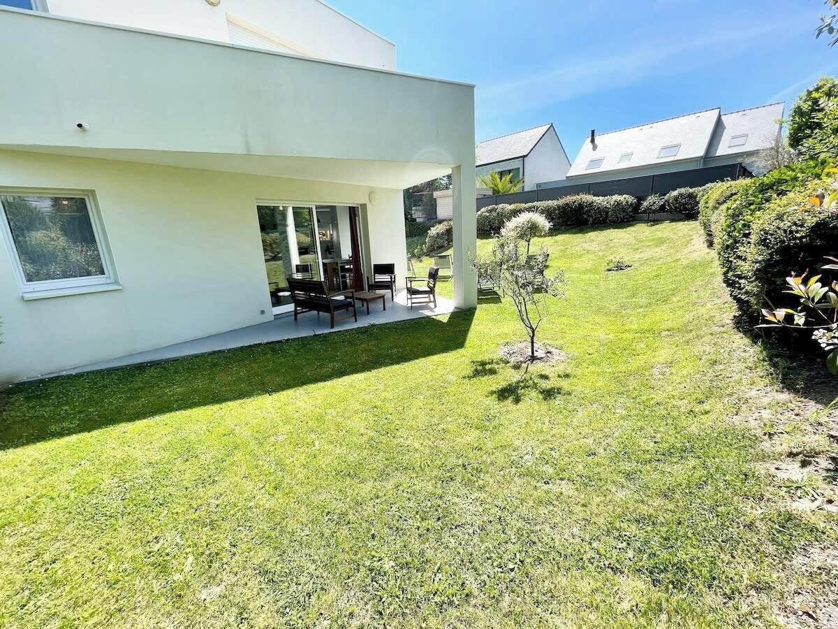 Una casa moderna con un porche cubierto, un césped pequeño y un jardín bien cuidado.