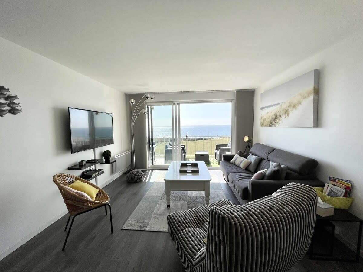 A modern living room with a flat-screen TV, a sofa, a striped armchair, and a coffee table.