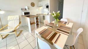 Une cuisine moderne avec des meubles blancs, un four à micro-ondes et une horloge au mur.