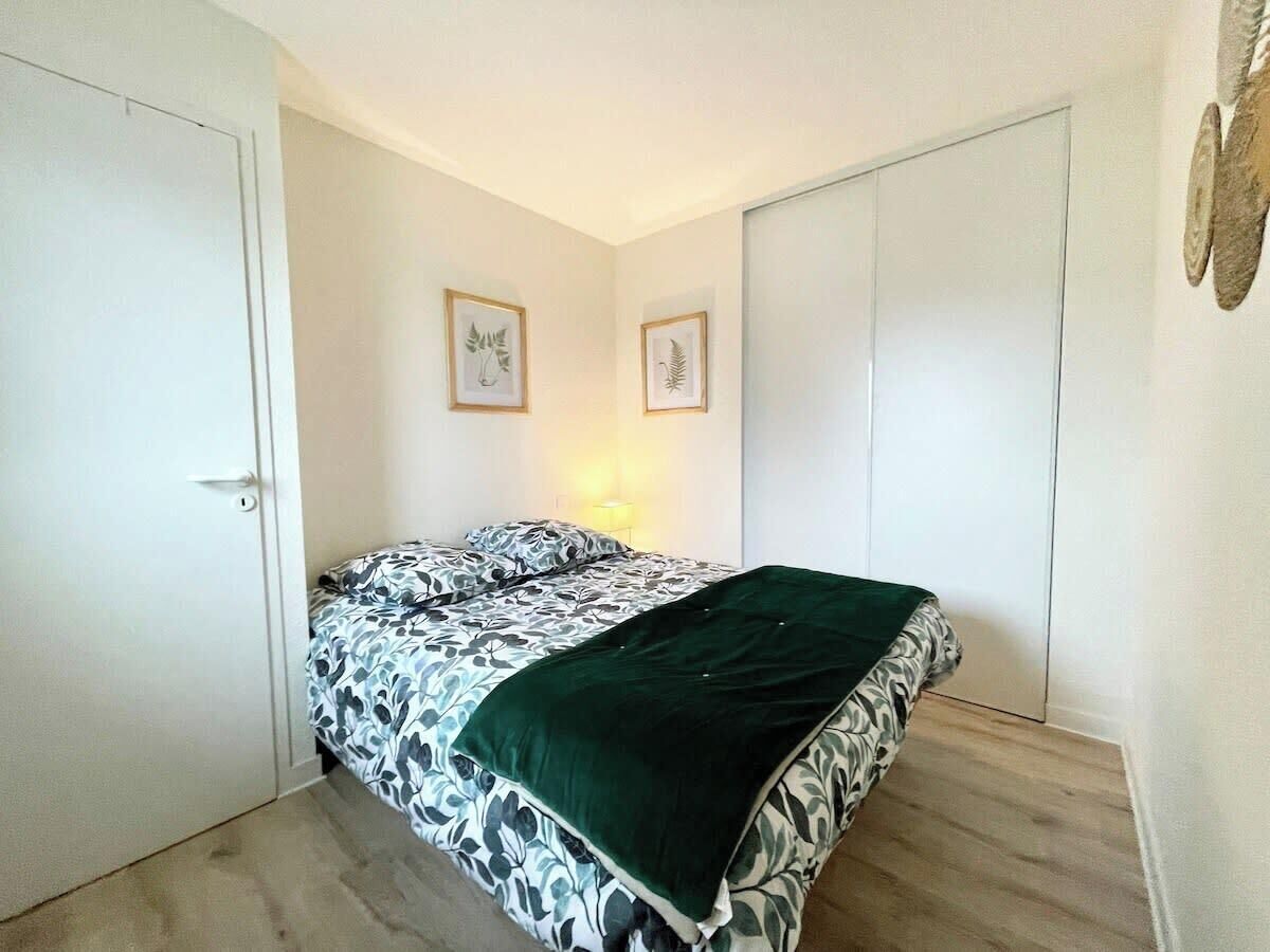 Een slaapkamer met een bed, een deur en twee foto's in lijsten aan de muur.