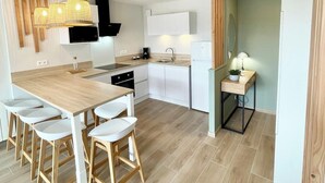 Eine moderne Küche mit einem Holzespeisetisch und Stühlen, einem eingebauten Ofen und einer Pendelleuchte.
