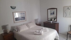 A bedroom with a large bed, a nightstand, a dresser, and a chair. - Impeccable 2-bed Apartment in Costa da Caparica (Almada)