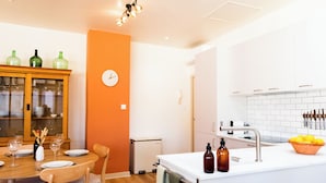 A modern kitchen with white cabinets, a sink, and a dining area with a wooden table and chairs.