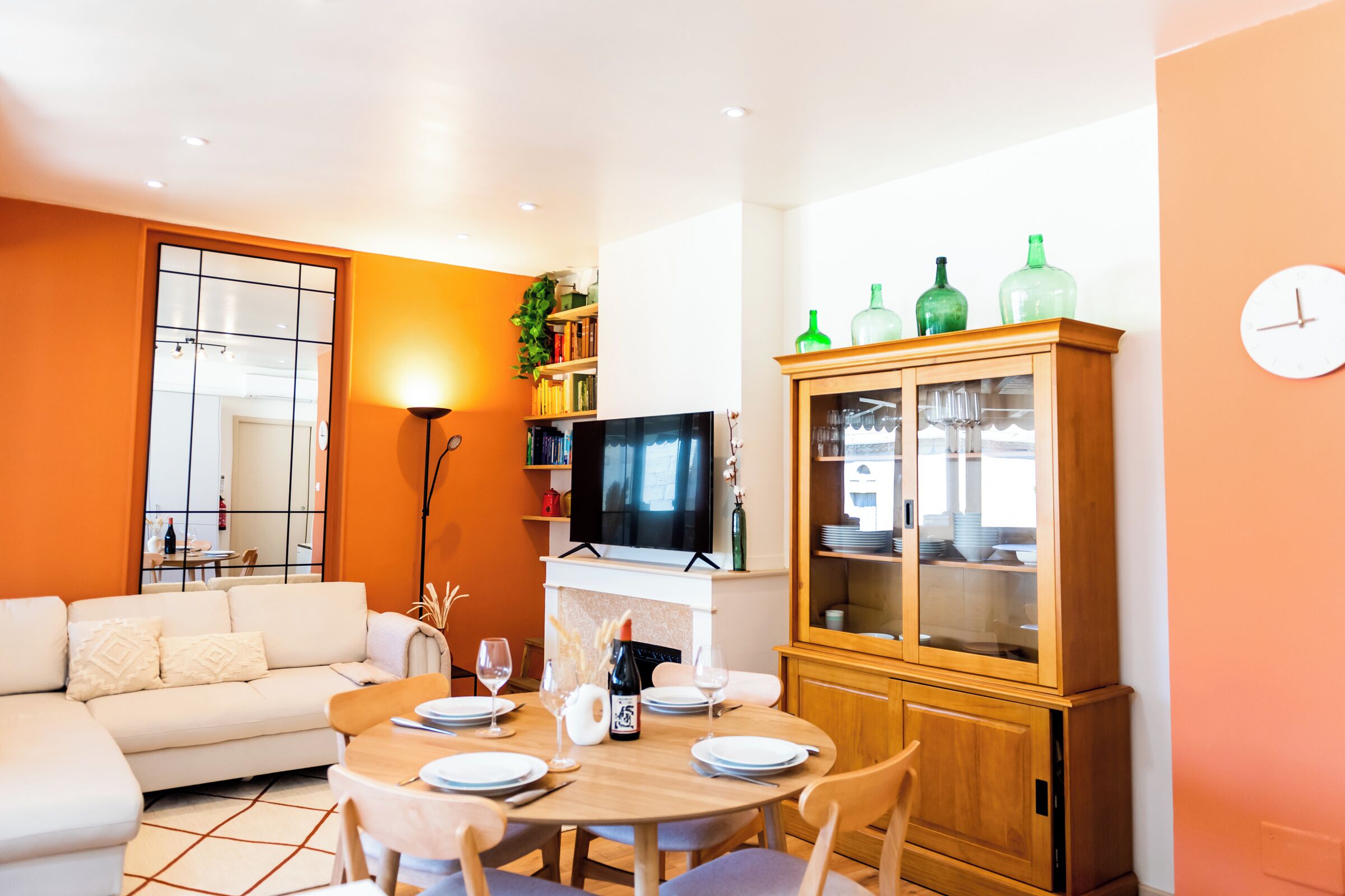 Ein Wohnzimmer mit einer Couch, einem Esstisch für zwei Personen, einem Fernseher und einer Vitrine.