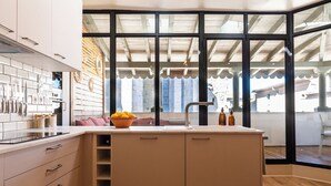 A modern kitchen with a large island, white cabinets, and a view through a glass door to an outdoor area.