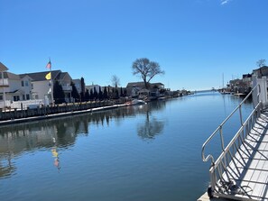 A calm waterfront with a dock, houses, and a clear sky.
