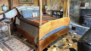 A four-poster bed with a wooden frame, a stone fireplace, and a bookshelf with books. - Magic Forest Farm's Mountain View Suite (Coeymans Hollow)