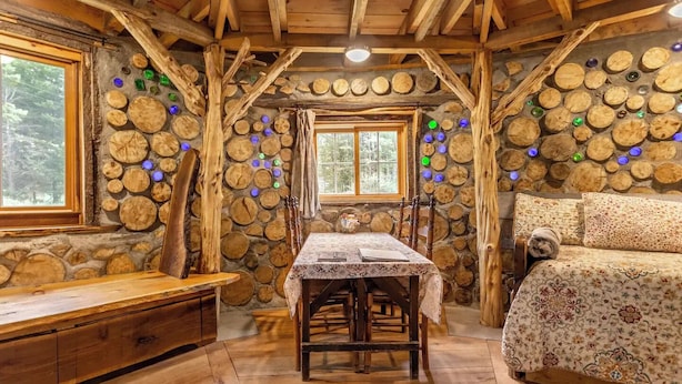 Ein rustikales Blockhaus-Interieur mit Steinwand, Holzmöbeln und einer gemütlichen Sitzecke.