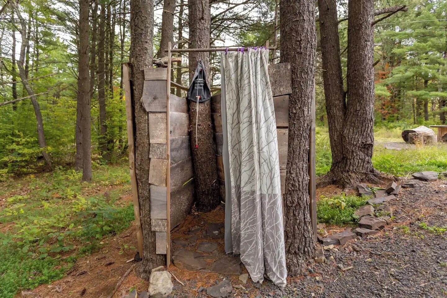 A rustic wooden structure with a metal door, a hanging bag, and a curtain.