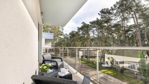 Ein Balkon mit Rattanmöbeln und Blick auf eine Wohngegend mit Häusern und Bäumen.