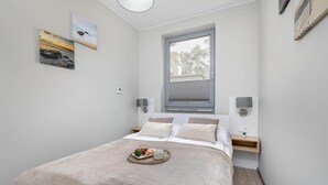 Ein modernes Schlafzimmer mit einem großen Bett, Nachttischen, einem Fenster mit Jalousien und Wandbildern.