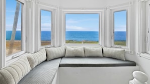 A room with a curved bench, large windows, and a view of the ocean.