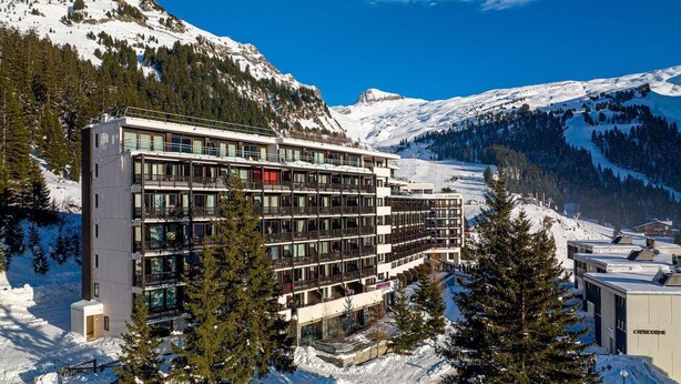 A multi-story hotel with balconies, surrounded by snow-covered mountains and trees. - Ski-in/ski-out & foot of the slopes, swimming pool, sauna, balcony, tv, ski locker, 45m², Flaine (Flaine)