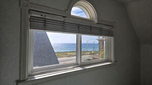 Ein Zimmer mit Fenster und Blick auf die Küste, einem Oberlicht und einer weißen Decke.