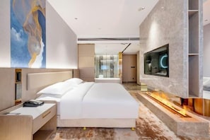 Une chambre d’hôtel moderne avec un grand lit, un téléviseur fixé au mur et une cheminée.