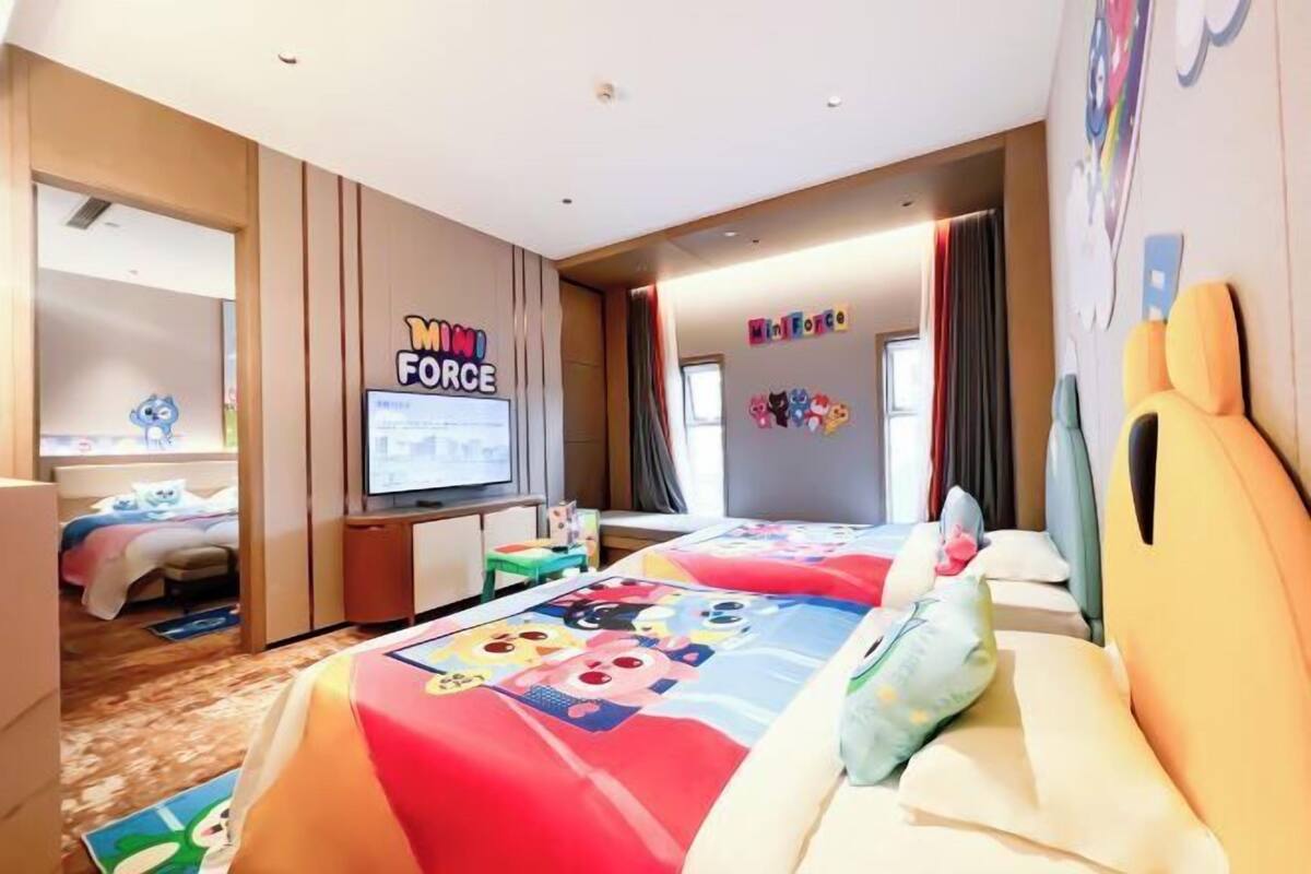 A hotel room with two beds, a TV, and a Minions-themed wall.