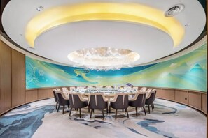 Uma sala de conferências com uma mesa redonda, cadeiras e um candelabro.