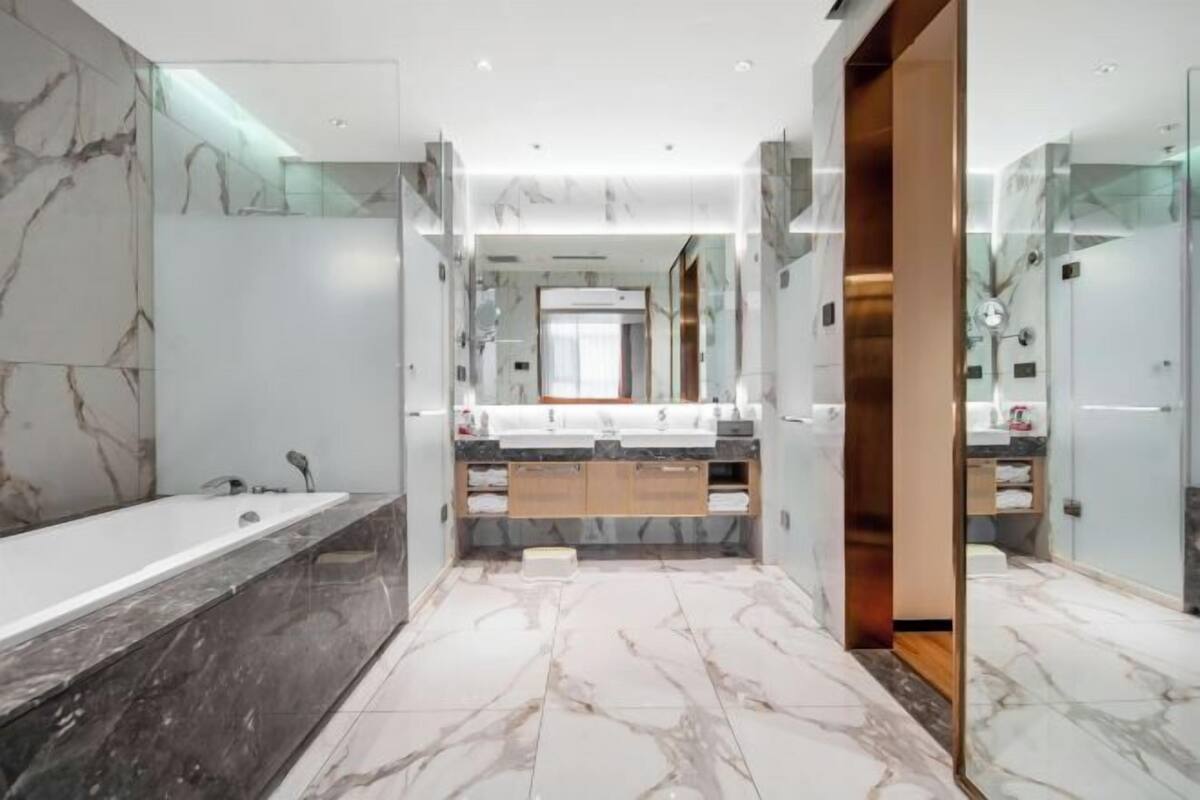 A modern bathroom with a large bathtub, dual sinks, and marble flooring.