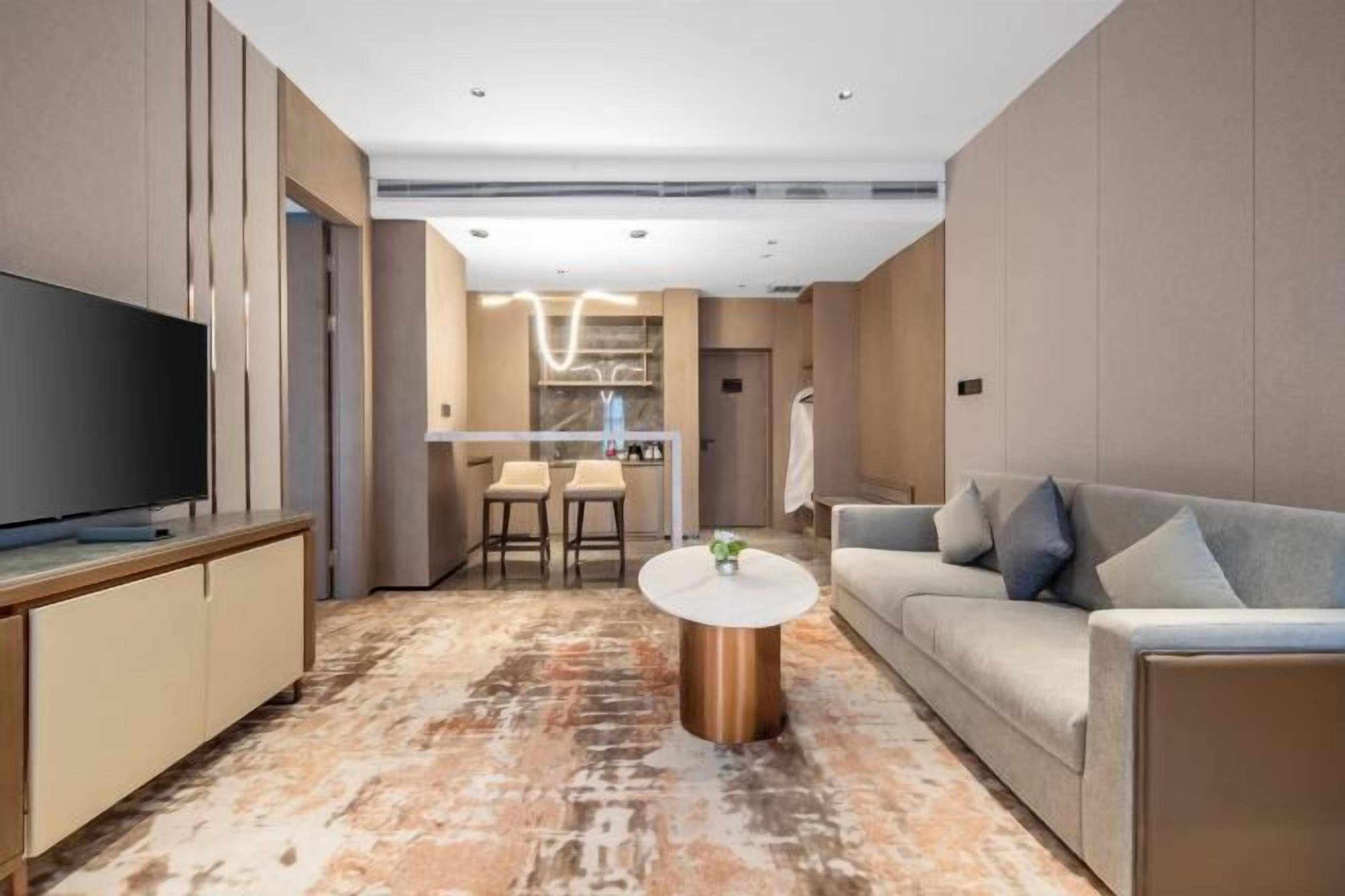 Ein modernes Wohnzimmer mit Flachbildfernseher, rundem Couchtisch, einer Couch und einem Essbereich mit Stühlen.
