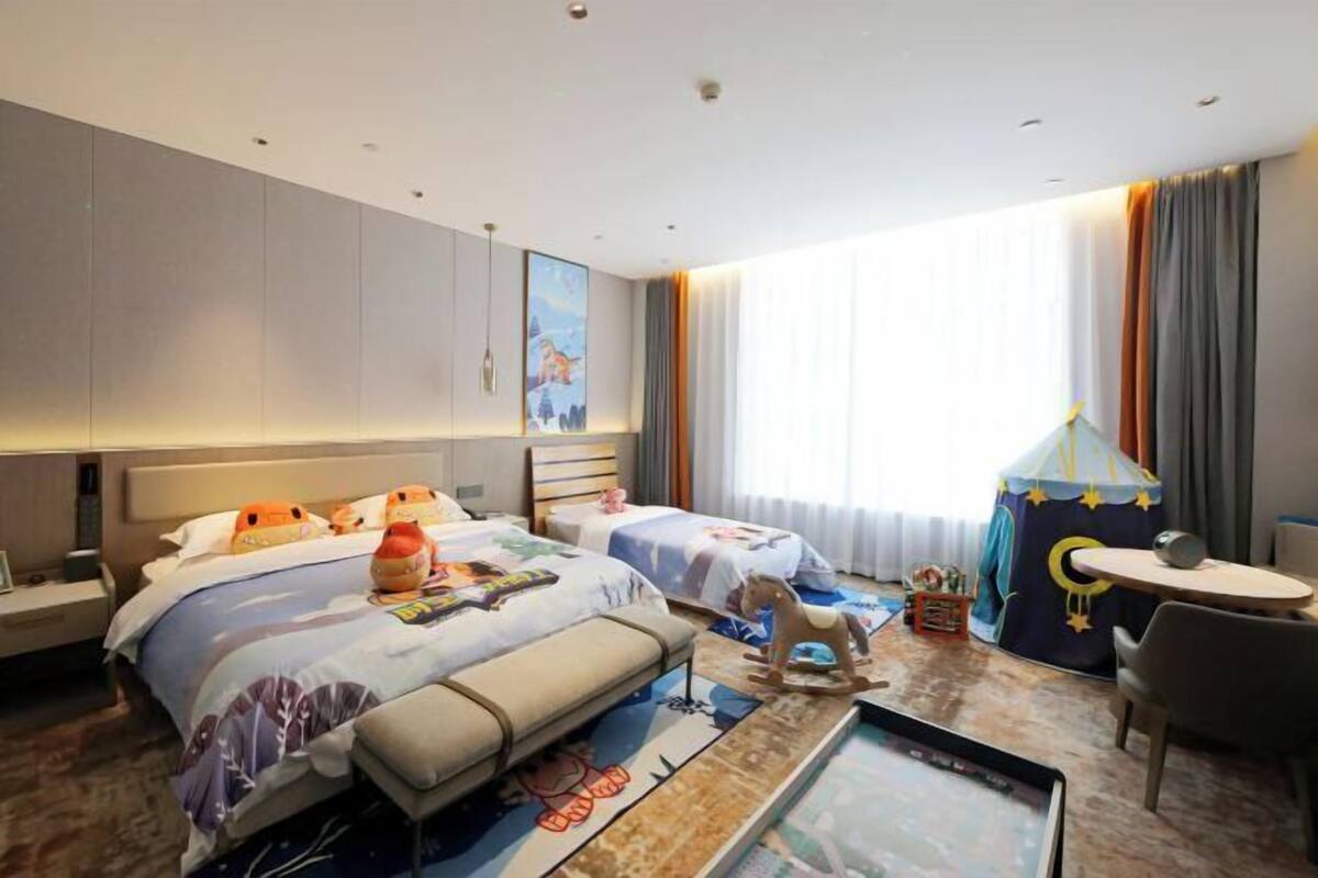 A hotel room with two beds, a desk, a chair, a small table, and a tent-like structure.