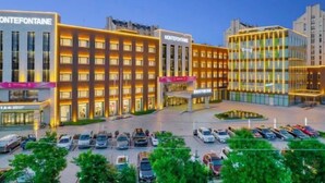 A hotel with multiple buildings, a parking lot, and a landscaped area with trees.