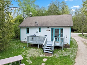 Ein kleines, eingeschossiges Gebäude mit Veranda, Treppe und einem Schild mit der Aufschrift 'CHALET 3'.