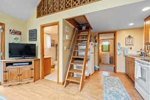 Une cuisine avec une échelle en bois, un téléviseur et un réfrigérateur.