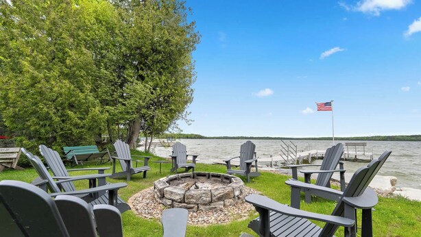 Un espace aménagé au bord du lac, avec des fauteuils Adirondack, un foyer et un drapeau américain.
