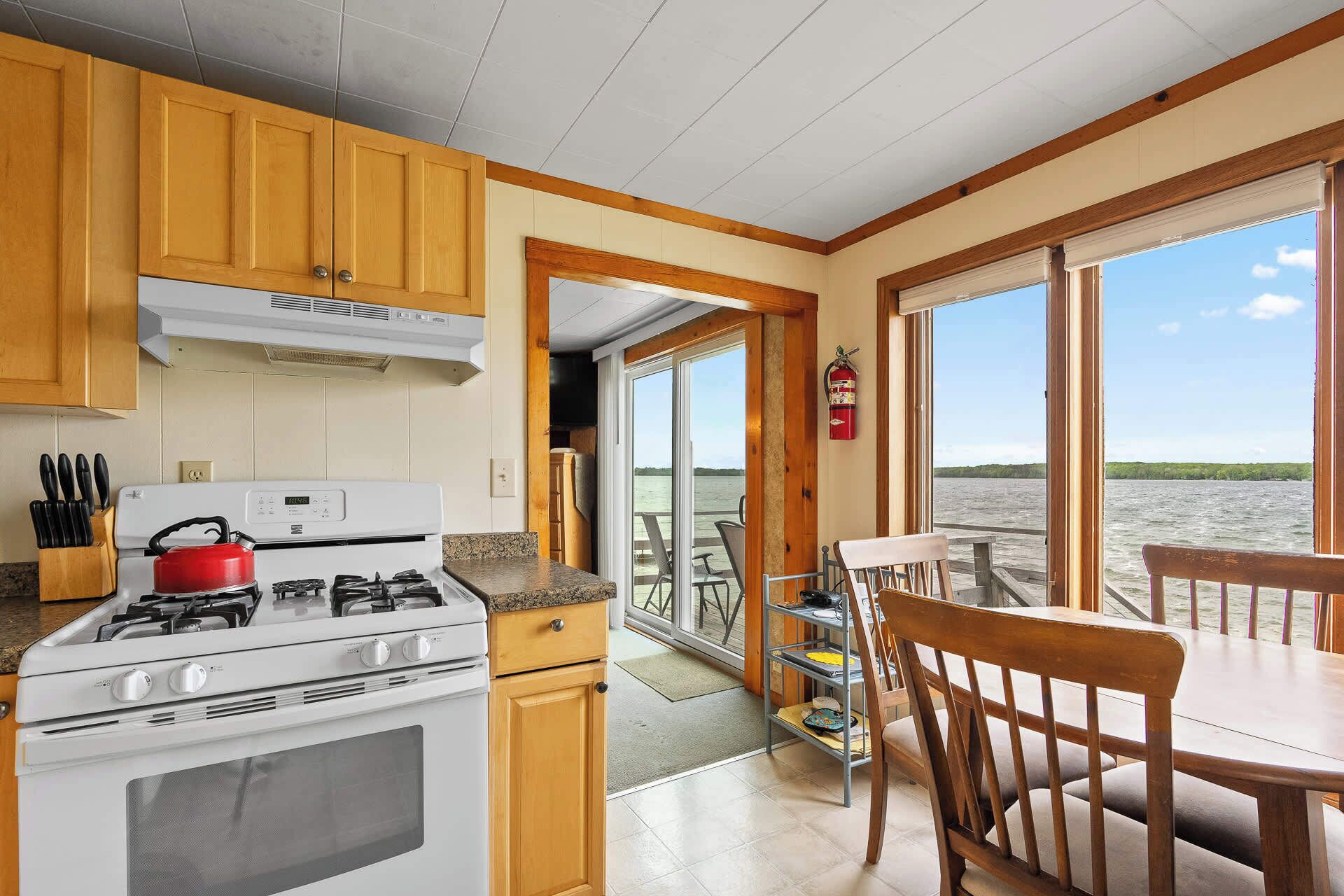 A kitchen with a stove, cabinets, and a view of the water.
